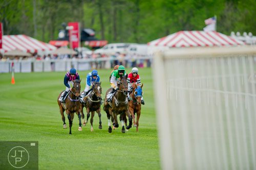Jockey Robert Walsh (center green) rides Mystery Jack as they lead the field down a straightaway in the Goose Island Beer Co. Maiden Claiming Hurdle during the 49th Annual Running of the Atlanta Steeplechase At Kingston Downs in Rome on Saturday, April 19, 2014. 