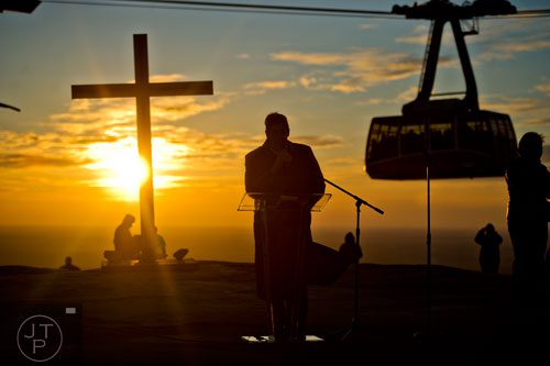 The sun rises on top of Stone Mountain as pastor Lamar Williams from the For Eternity Christian Church gives the call to worship and prayer during the 70th annual Easter Sunrise Service on Sunday, April 20, 2014. 