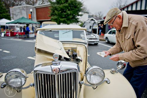 George Hayes wipes rain off of his 1950 MG-TD during the Great British Car Fayre in downtown Alpharetta on Saturday, March 29, 2014. 