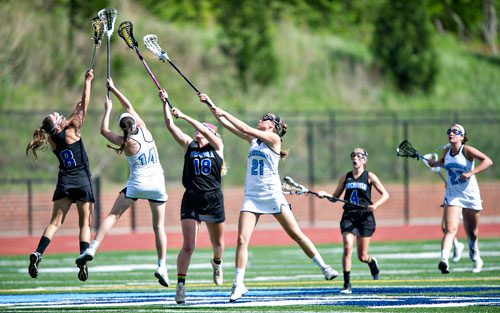 Cambridge's Jill Haight (14) and Melissa Birdsell (21) and Lake Norman's Jordyn King (8) and RoseAnna Schiemer (18) leap into the air to try and get control of the ball on Friday, April 25, 2014.