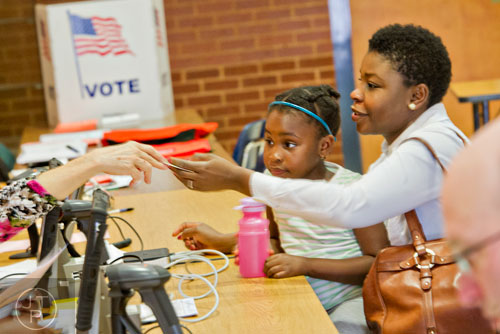 Felicia McCall (right) holds her daughter Fadzwa in her lap as she checks in to vote at the North Fulton polling location at Centennial High School in Roswell on Tuesday, May 20, 2014. 