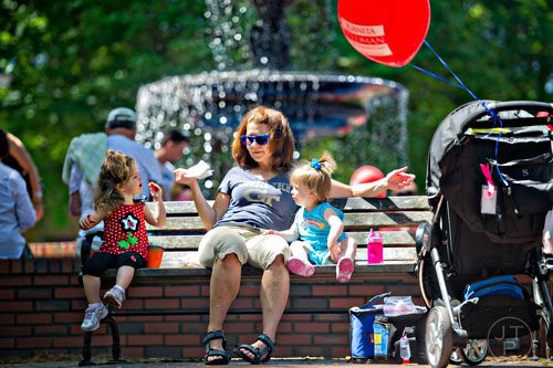 Tammy Shiflett (center) eats a snack with her granddaughter Lowery Collins (left) and niece Claire Shiflett as they sit on a bench during the May-retta Daze Arts & Craft Festival at Glover Park in Marietta on Sunday, May 4, 2014. 