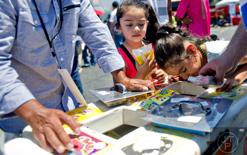 Joselyn Correa (right) and her sister Janice figure out which type of ice cream bar they want during the Cinco de Mayo Festival at Plaza Fiesta in Atlanta on Sunday, May 4, 2014.