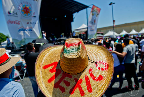 Noe Zanudio (center) keeps the sun at bay with a giant straw hat as he watches the stage during the Cinco de Mayo Festival at Plaza Fiesta in Atlanta on Sunday, May 4, 2014. 