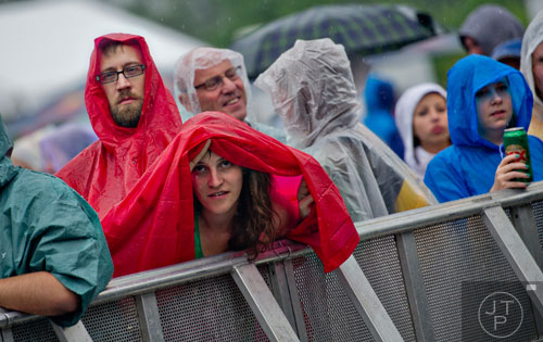 Jason Christensen (left) and Sydney Whitlock hide from the rain under a poncho during the Shaky Knees Music Festival at Atlantic Station in Atlanta on Friday, May 9, 2014.