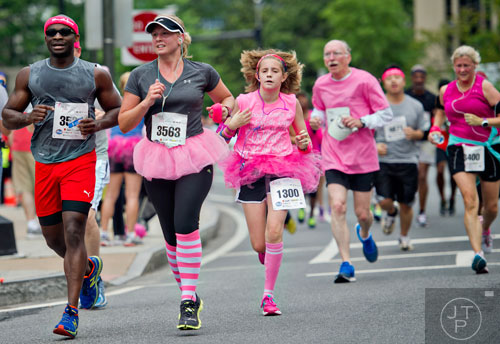 Wole Ogunlana (left), Angela Baumann and Samantha Humphrey run down Peachtree Rd. during the Susan G. Komen Race for the Cure in Atlanta on Saturday, May 10, 2014. 