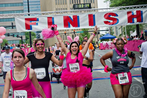 Nika Golshani (center) raises her hands in the air as she and Gracie Perez (left) cross the finish line for the Susan G. Komen Race for the Cure at Lenox Square Mall on Saturday, May 10, 2014. 