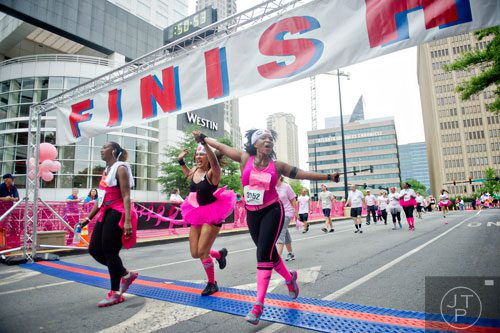 Chi Michaels (right) and Leesa Mendes hold hands as they cross the finish line for the Susan G. Komen Race for the Cure at Lenox Square Mall on Saturday, May 10, 2014. 