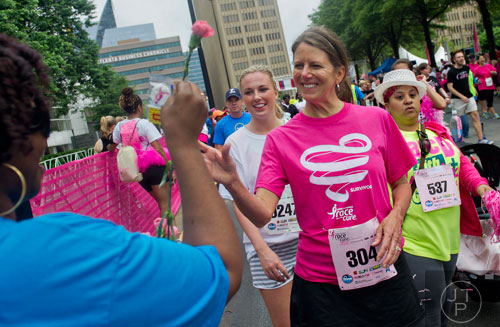Patty Cheek (center) is handed a rose after crossing the finish line for the Susan G. Komen Race for the Cure at Lenox Square Mall on Saturday, May 10, 2014. 