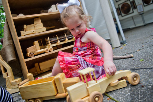 Ivey Dukes tries to decide which is her favorite wooden toy in front of Kevin May's booth during the Buckhead Spring Arts & Crafts Festival at Chastain Park in Atlanta on Saturday, May 10, 2014. 
