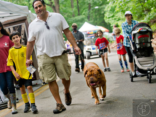 Nolan Alexander (left) holds hands with his father Michael as they walk their French mastiff Ginger past artists' booths during the Buckhead Spring Arts & Crafts Festival at Chastain Park in Atlanta on Saturday, May 10, 2014. 