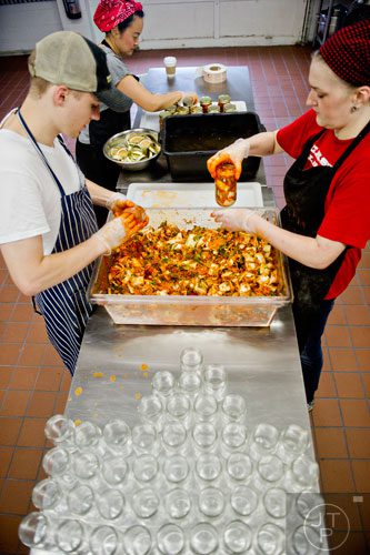 Ben Wills (left) and Lollie Nabors (right) fill jars with freshly prepared kimchi as Hannah Chung screws lids on already filled jars at the Simply Seoul Kitchen in Decatur on Thursday, May 15, 2014.    