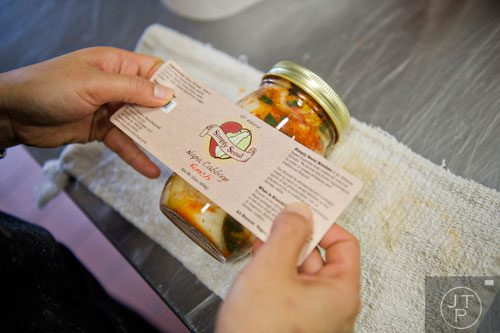 Hannah Chung places labels on jars of kimchi at the Simply Seoul Kitchen in Decatur on Thursday, May 15, 2014.  