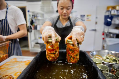 Hannah Chung rinses jars of kimchi at the Simply Seoul Kitchen in Decatur on Thursday, May 15, 2014. 