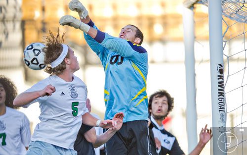 McIntosh's Nicholas Alvey (5) goes up tp head the ball as Houston County goalie Bryce Dawson knocks the ball away during the Class AAAAA championship game at Kennesaw State University on Friday, May 16, 2014.  