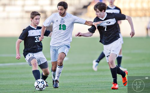 McIntosh's Adam Sheikali (19) weaves the ball past Houston County's Kade Randall (33) and Tim Freeman (7) during the Class AAAAA championship game at Kennesaw State University on Friday, May 16, 2014.  