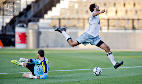 McIntosh's Adam Sheikali (right) misses a shot on goal as he leaps over Houston County goalie Bryce Dawson (left) during the Class AAAAA championship game at Kennesaw State University on Friday, May 16, 2014. 