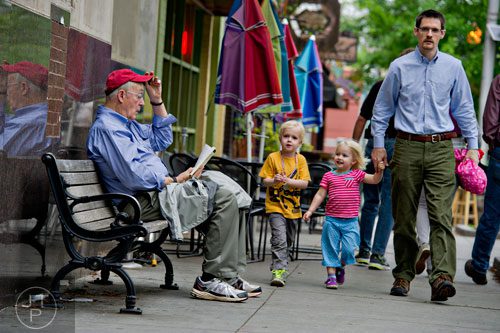 Michael Connor (right) walks with his children Aila and Erik as they pass a man reading on a bench in downtown Decatur on Wednesday, April 30, 2014.  