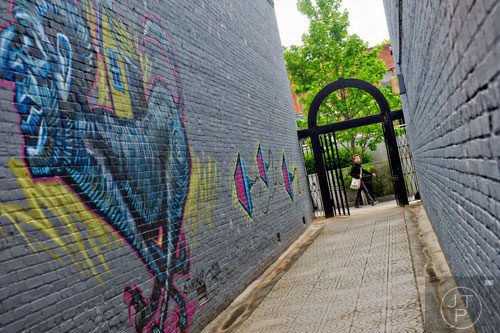 Nickolas Fields passes by an alleyway with graffiti on the wall in downtown Decatur on Wednesday, April 30, 2014.