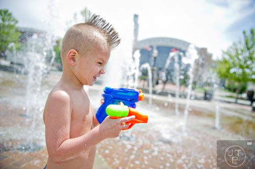 Nolan Hardee plays with waterguns at the fountains in front of city hall in downtown Suwanee on Thursday, May 1, 2014. 