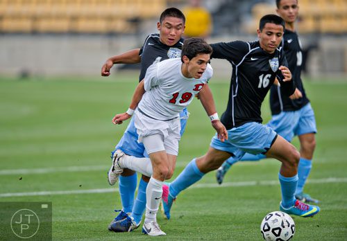 Dalton's Javier Rodriguez (19) moves the ball past Johnson's Isaac Henry (left) and Alberto Deltoro (16) during the Class AAAA championship soccer game at Kennesaw State University on Saturday, May 17, 2014.