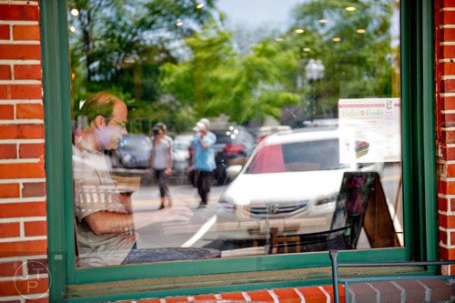 Eric Ridenour works by the window of a coffee shop in downtown Norcross on Thursday, May 1, 2014.   