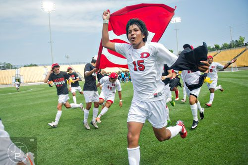 Dalton's Edgar Hernandez (15) runs around the field carrying the Dalton HIgh School flag after defeating Johnson 2-0 during the Class AAAA championship soccer game at Kennesaw State University on Saturday, May 17, 2014.  