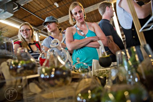 Jennifer Burnett (right), Carrie Hamilton and Cicely Berg look at the plants for sale at the ZEN Succulent booth during the Indie Craft Experience at Ambient Plus Studio in Atlanta on Saturday, June 28, 2014. 