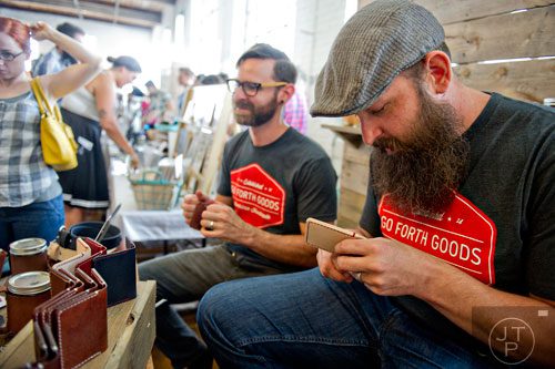 Joel Koeppen (right) and Nathan Martin punch holes in leather wallets during the Indie Craft Experience at Ambient Plus Studio in Atlanta on Saturday, June 28, 2014. 