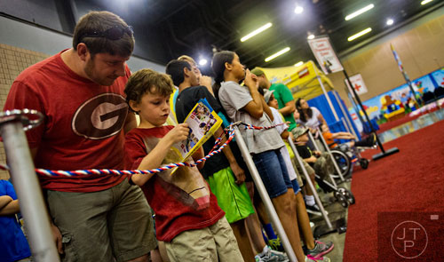 Nathan Williams (left) and his son Corbin plan out their plan of attack before the gates open to the LEGO KidsFest at the Cobb Galleria Centre in Atlanta on Saturday, June 28, 2014. 
