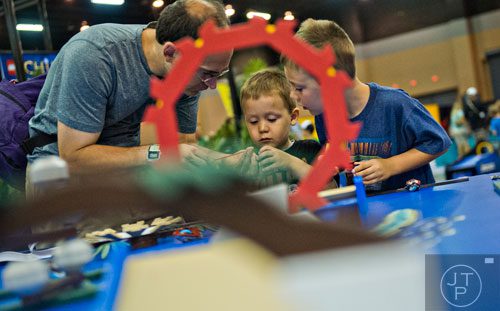 Michael Black (left) helps his sons Caleb and Joshua launch LEGO racers off of ramps during the LEGO KidsFest at the Cobb Galleria Centre in Atlanta on Saturday, June 28, 2014. 
