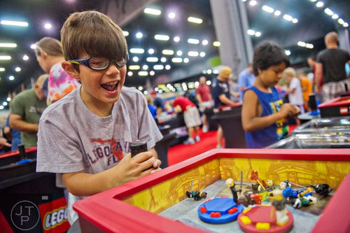 Landon Guzman (left) celebrates as he knocks down his father's LEGO characters during the LEGO KidsFest at the Cobb Galleria Centre in Atlanta on Saturday, June 28, 2014. 