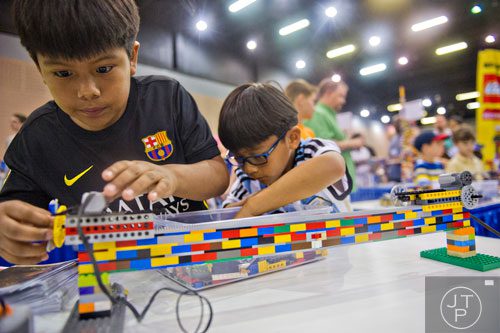 Richard Perez (left) and his brother Xavi build motorized cars to crash into one another during the LEGO KidsFest at the Cobb Galleria Centre in Atlanta on Saturday, June 28, 2014.