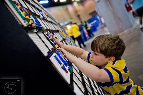 Logan Keene presses his LEGO artwork onto a wall during the LEGO KidsFest at the Cobb Galleria Centre in Atlanta on Saturday, June 28, 2014.