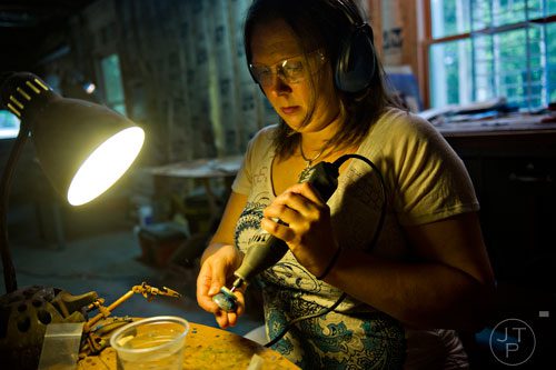 Megan Austin uses an electric tool to polish a piece of emerald as she makes jewelry at her home in Canton on Tuesday, May 27, 2014.  