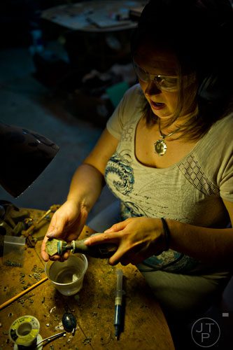 Megan Austin uses an electric tool to polish a piece of emerald as she makes jewelry at her home in Canton on Tuesday, May 27, 2014.  