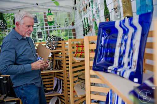 Thomas Deans looks at glasswork in Brenda Biberdorf's booth as he judges artwork during the Third Annual Peachtree Hills Festival of the Arts in Atlanta on Saturday, May 31, 2014. 