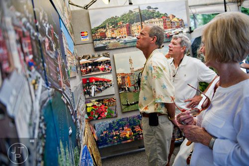 Tom Biery (left) and George and Kathy Boltwood look at artwork on display in James Erickson's booth during the Third Annual Peachtree Hills Festival of the Arts in Atlanta on Saturday, May 31, 2014. 