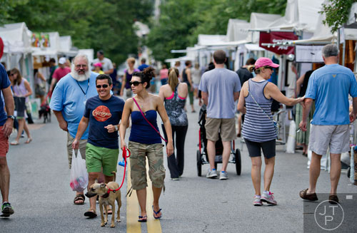 Scott Moore (left) and his wife Laura walk their dog Stella as they check out the booths during the Third Annual Peachtree Hills Festival of the Arts in Atlanta on Saturday, May 31, 2014. 