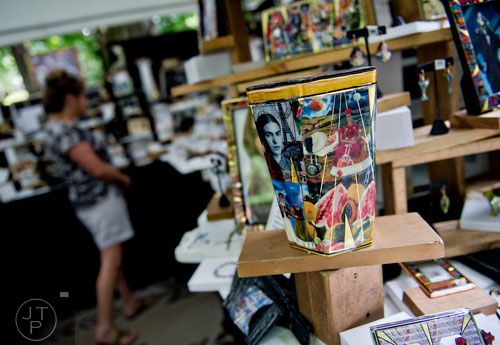 Artwork sits on display in John T. Crutchfield's booth as Dawn Macksood looks around during the Third Annual Peachtree Hills Festival of the Arts in Atlanta on Saturday, May 31, 2014. 