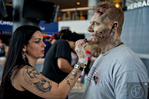 Stephanie Anderson (left) applies makeup to Sean Henderson's face to make him look like a walker during The Walking Dead Escape event at Philips Arena in Atlanta on Saturday, May 31, 2014. 