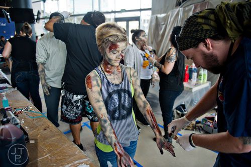Alex Petty (right) applies makeup to Lauren Dobson's arms and hands to make her look like a walker during The Walking Dead Escape event at Philips Arena in Atlanta on Saturday, May 31, 2014. 