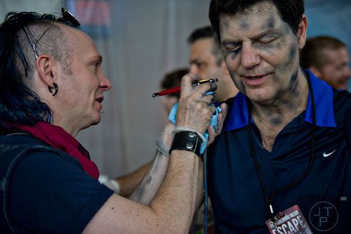 Greg Bivens (left) applies makeup to Jay Klapper's face to make him look like a walker during The Walking Dead Escape event at Philips Arena in Atlanta on Saturday, May 31, 2014. 
