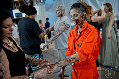 Kristina Ballenger (right) has blood applied to her hands and arms to make her look like a walker by Stephanie Anderson (left) during The Walking Dead Escape event at Philips Arena in Atlanta on Saturday, May 31, 2014. 