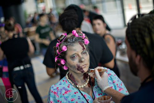 Amy Poole (center) has blood applied to her neck and face to make her look like a walker during The Walking Dead Escape event at Philips Arena in Atlanta on Saturday, May 31, 2014. 