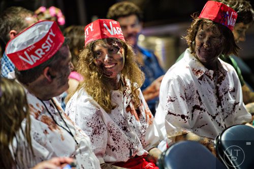 Dressed as walker Varsity employees, Katie Smith (center) sits with her parents Ed and Suzy as they wait for the start of The Walking Dead Escape event at Philips Arena in Atlanta on Saturday, May 31, 2014. 