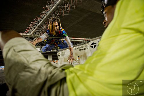 Valerie Hall (top) reaches down to try and infect participants as they make their way through The Walking Dead Escape event at Philips Arena in Atlanta on Saturday, May 31, 2014. 