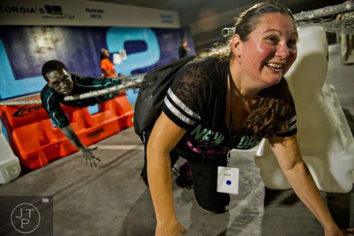 Pam Bryan (right) crawls past Phillip Hoke (top) as he tries to infect participants during The Walking Dead Escape event at Philips Arena in Atlanta on Saturday, May 31, 2014. 