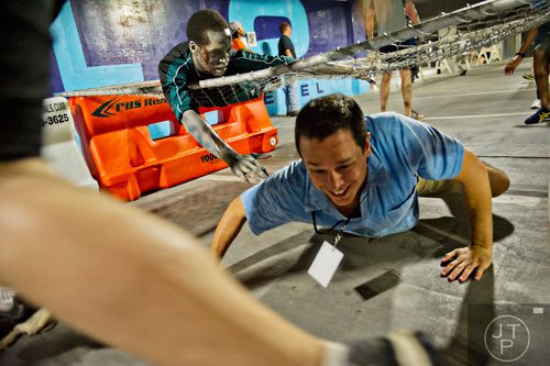 Phillip Hoke (top) reaches down to try and infect participants as they make their way through The Walking Dead Escape event at Philips Arena in Atlanta on Saturday, May 31, 2014. 