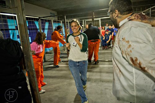 Jennifer Cook (center) runs past walkers during The Walking Dead Escape event at Philips Arena in Atlanta on Saturday, May 31, 2014. 